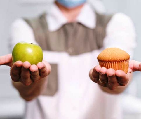 photo d'une personne qui tient une pomme et un gateau dans chaque mains